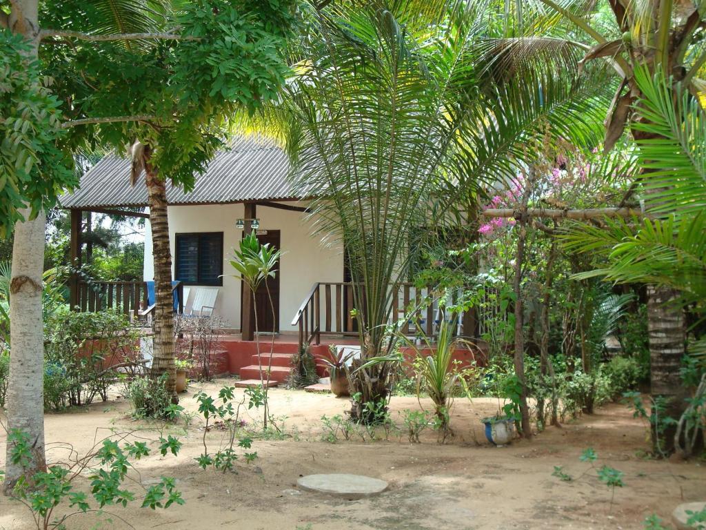 una casa con muchas palmeras delante de ella en Hotel Village Vacances Awale Plage, en Grand-Popo