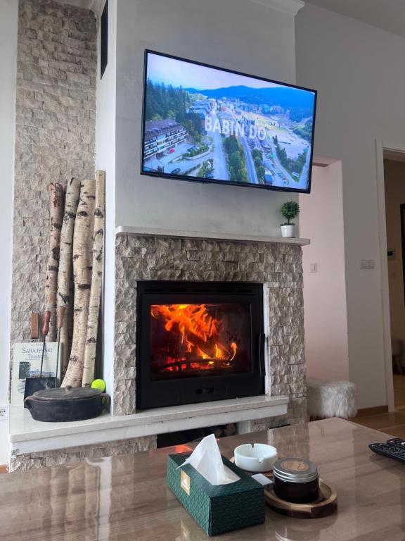 a living room with a fireplace with a television above it at Srna Apartment - Bjelašnica in Bjelašnica