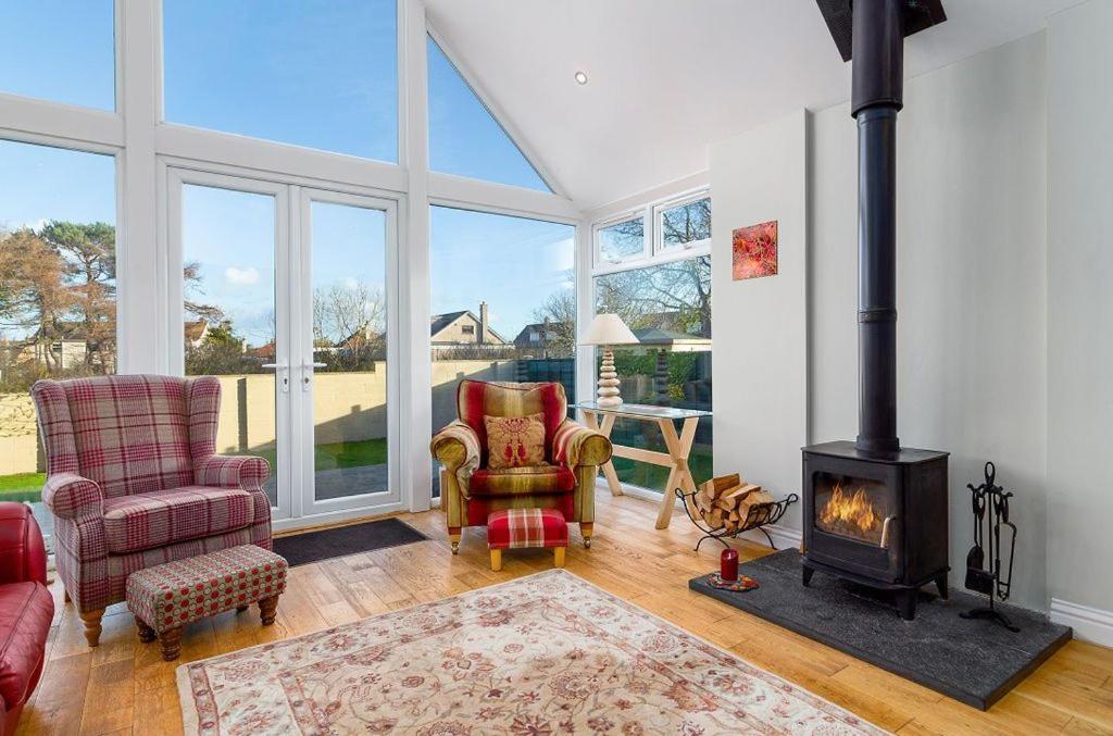 a living room with a fireplace and two chairs and a stove at Kilrymont View in St. Andrews