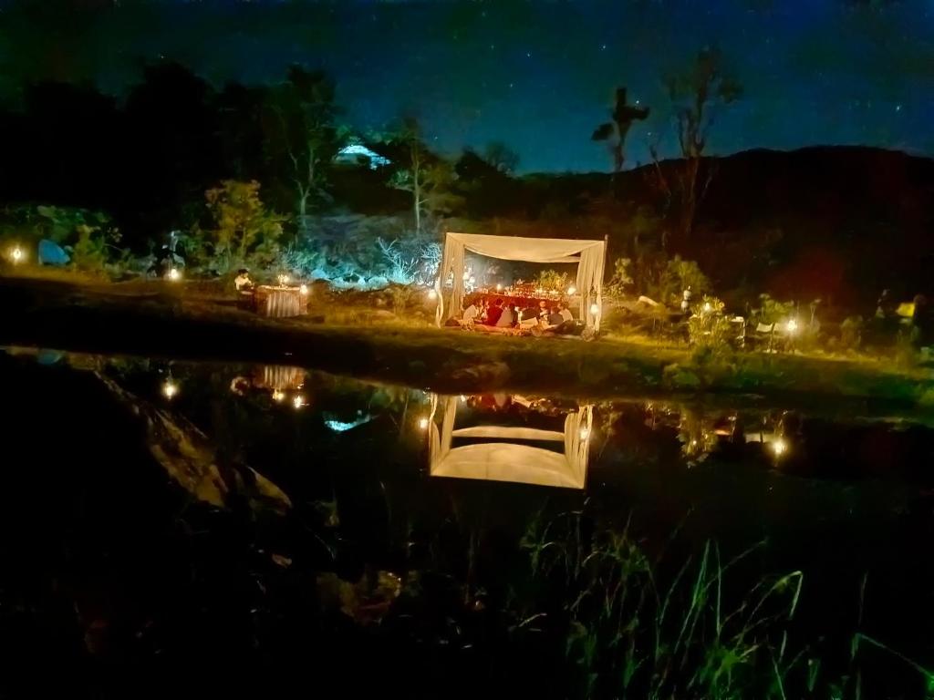a tent on the edge of a body of water at night at The Jungle Lust in Kumbhalgarh