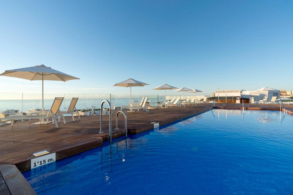 una piscina con sillas y sombrillas en un edificio en Aluasun Lago Rojo - Adults recommended, en Torremolinos