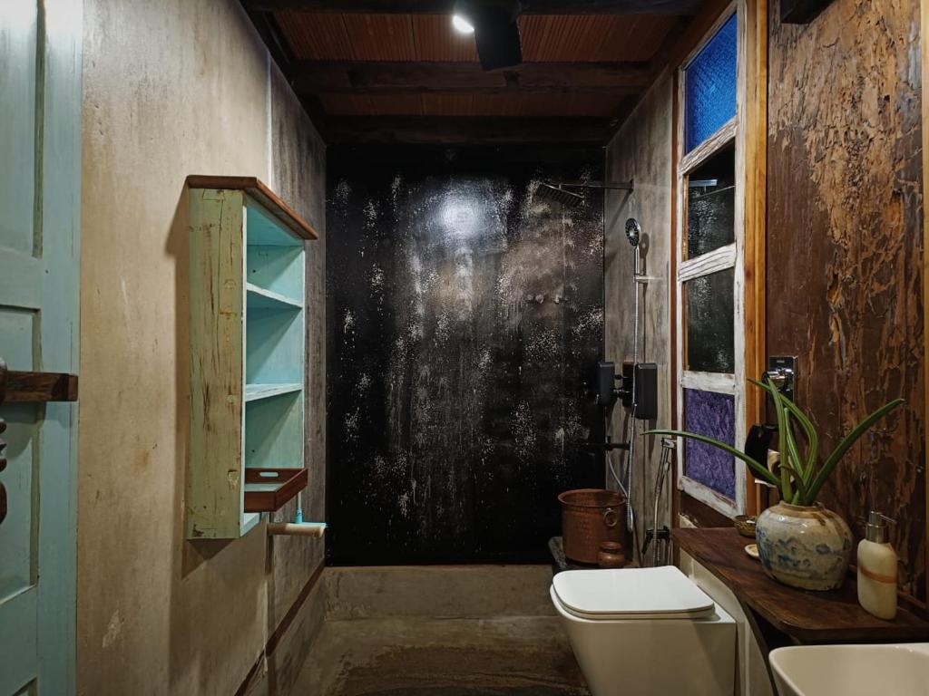 a bathroom with a toilet and a window at Svarna in Udupi
