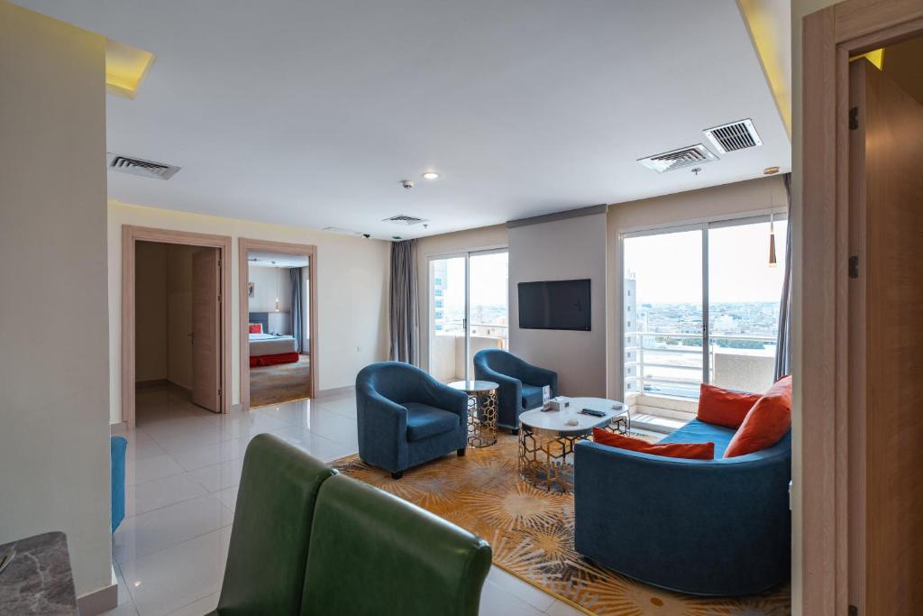 sala de estar con sillas, sofá y TV en Wahaj Boulevard Hotel Apartmentوهج بوليفارد للشقق الفندقية, en Kuwait