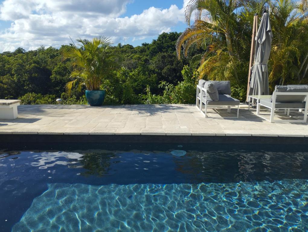 大博格Bas de villa vue mer avec deux chambres的一个带两把椅子和遮阳伞的游泳池