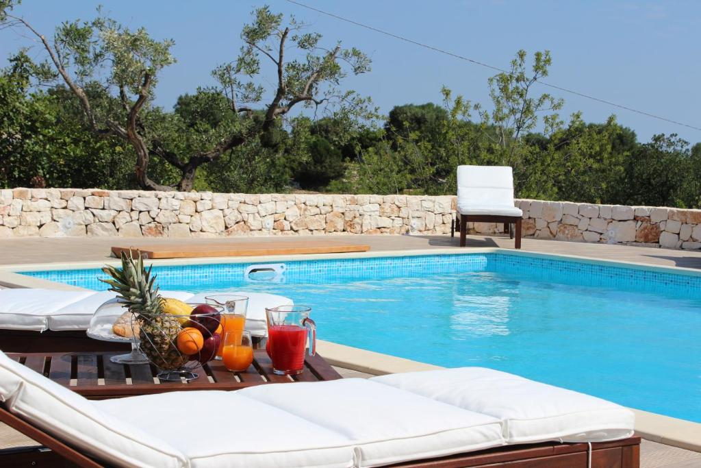 een zwembad met een tafel met drankjes erop bij Villa Mest Pepp in Monopoli
