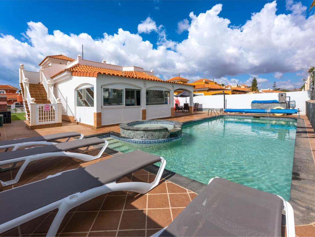 a swimming pool with chairs and a house at PRIMERA LUXURY HOUSE in Caleta De Fuste