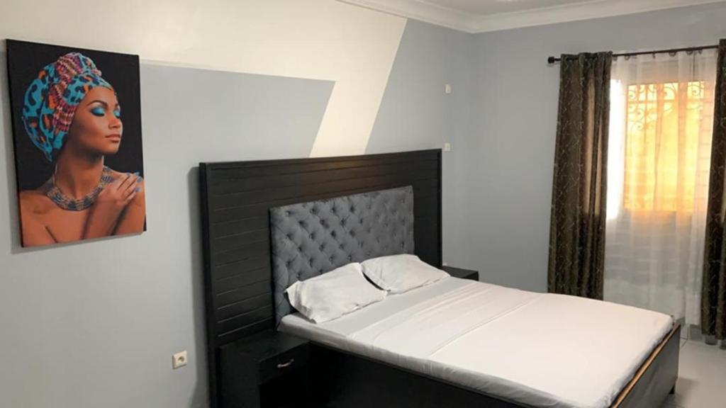 1 dormitorio con 1 cama con una foto en la pared en PNHouse Anguissa A2, en Yaoundé