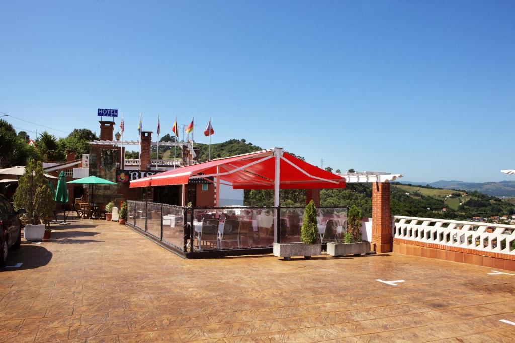 a restaurant with a red umbrella on a roof at Hotel Risco in Laredo