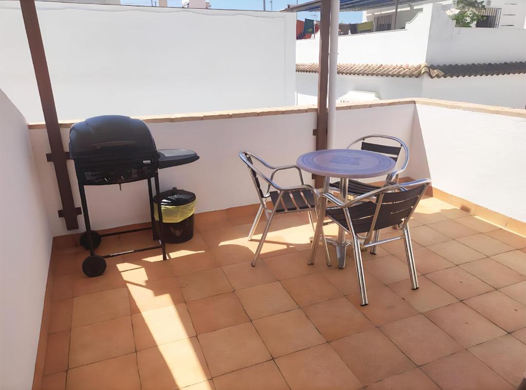 einen Balkon mit einem Tisch, Stühlen und einem Grill in der Unterkunft Casa con Terraza y Barbacoa en el Casco Antiguo in Barbate