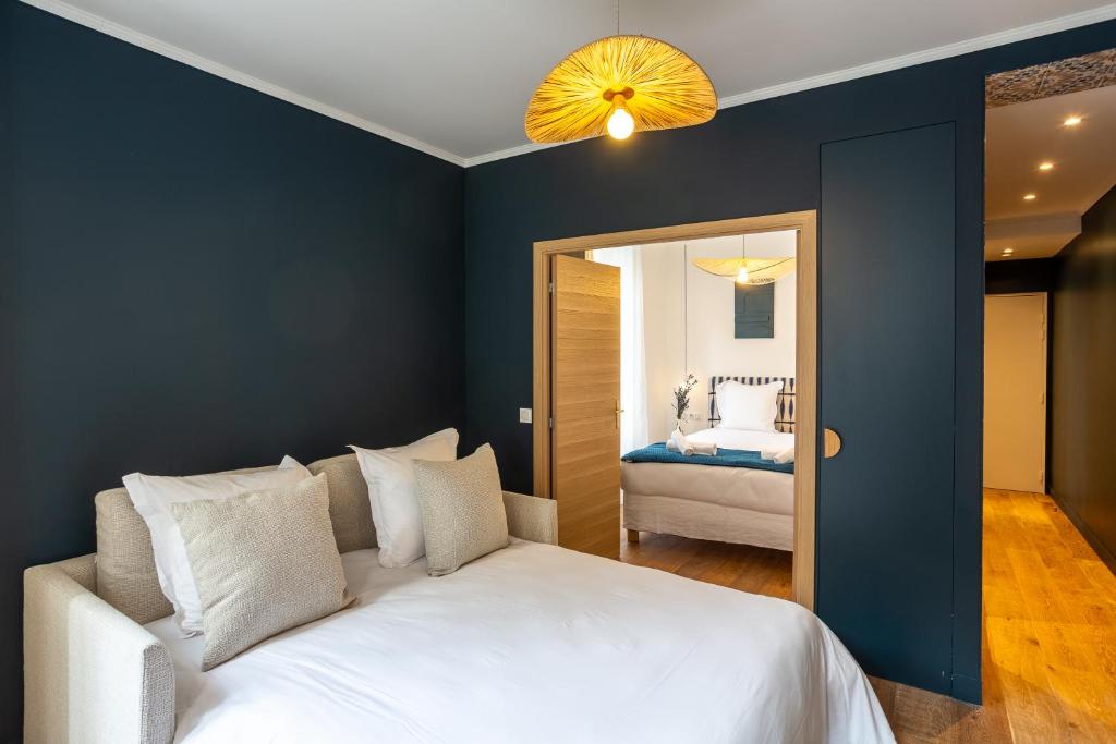 a bedroom with a large white bed and a room with a bed sqor at The Blue Suite Downtown Montmartre in Paris