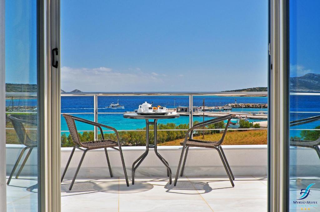 a balcony with a table and two chairs and the ocean at Myrto Hotel in Koufonisia