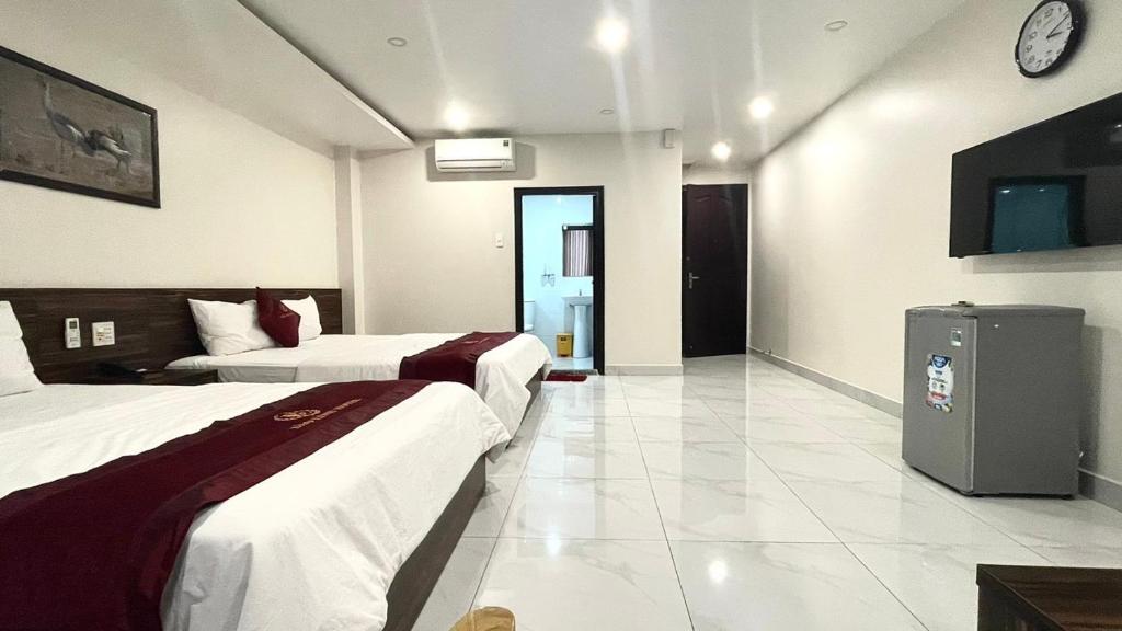 um quarto de hotel com duas camas e um relógio na parede em Khách sạn Bảo Linh em Tràm Chim