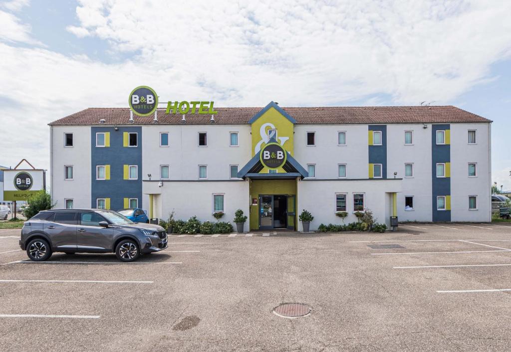 een hotel met een auto geparkeerd op een parkeerplaats bij B&B HOTEL Mulhouse Ile Napoléon in Illzach