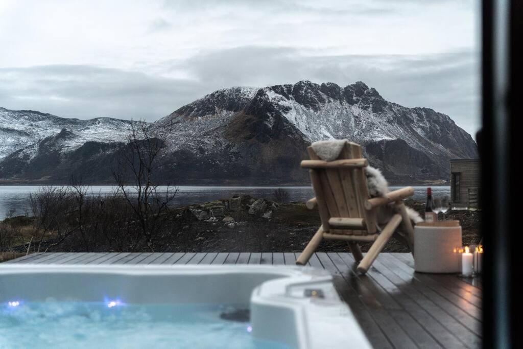 a chair sitting next to a tub with a mountain at Luksushytte med Jacuzzi, Summer&Winter Retreat in Lyngværet