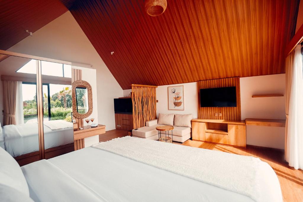 a large bedroom with a bed and a television at Padi Villas by Aayan in Canggu