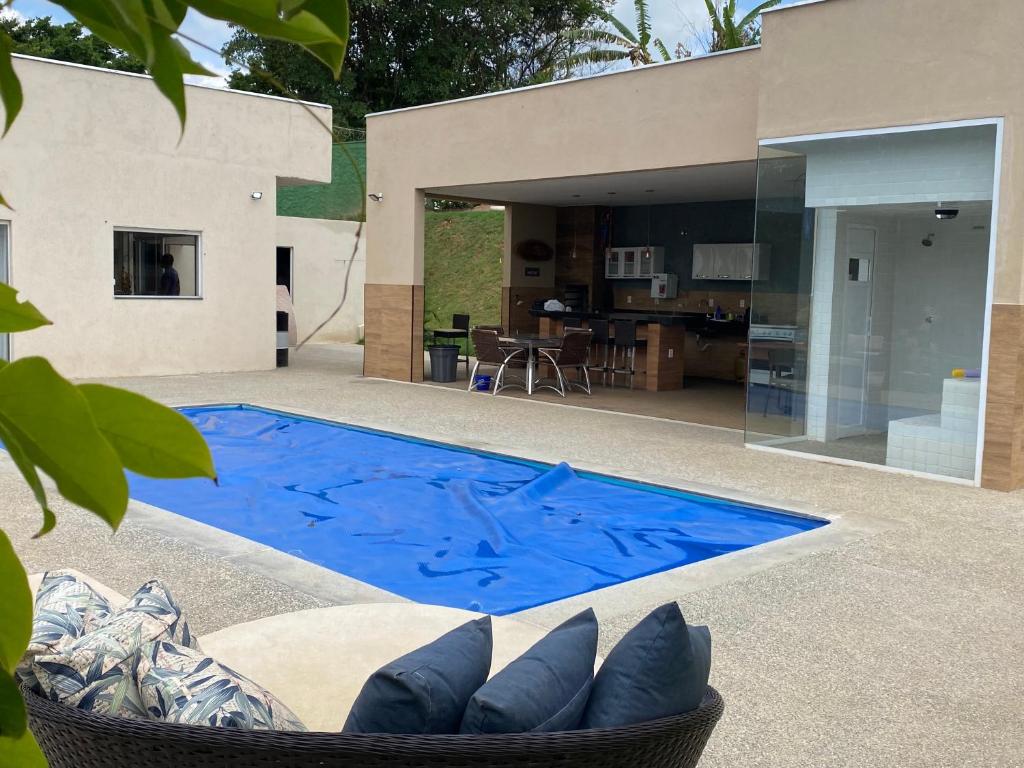 a blue swimming pool in front of a house at Sitio Silveira Nobre - São Joaquim de Bicas in São Joaquim de Bicas