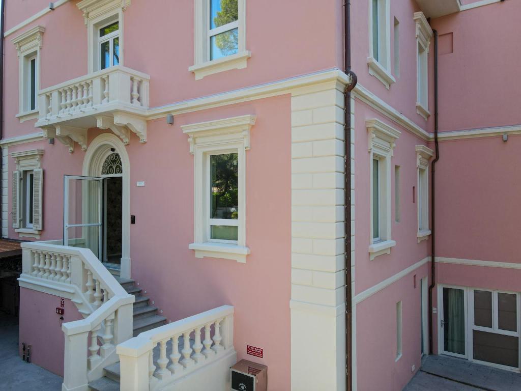 a pink house with stairs and a balcony at Castiglioncello Suite in Castiglioncello