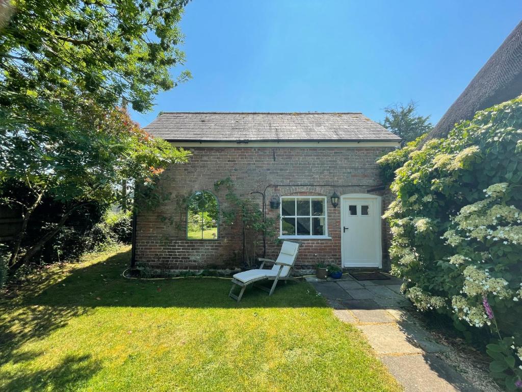 a small brick house with a chair in the yard at Little Barn in Dorchester