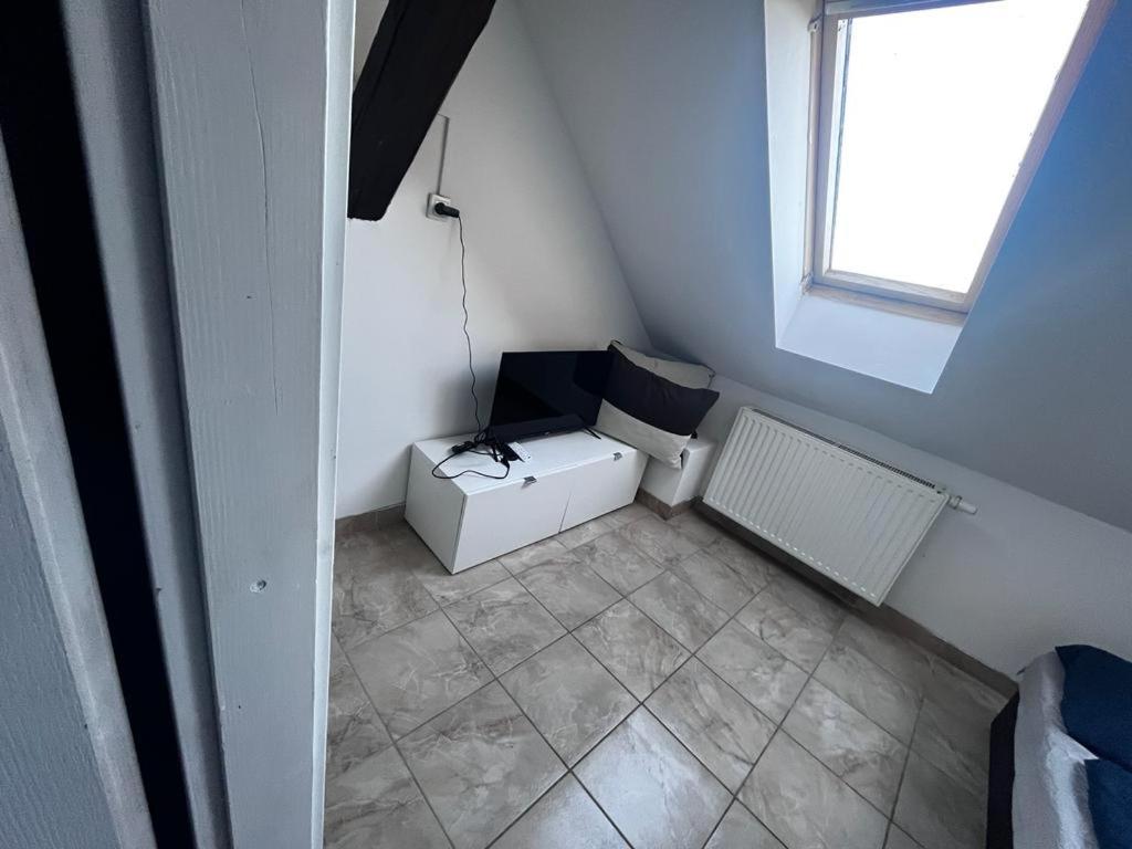 a small attic room with a heater and a window at Budget Inn th 23 - Downtown 3 Bedroom apartment in Szombathely