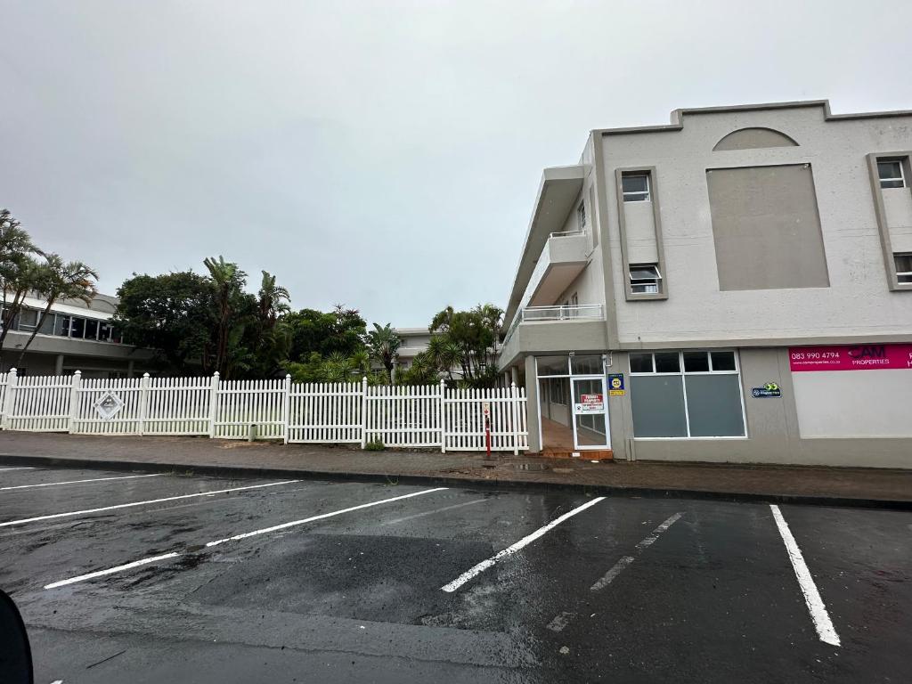 a building with a white fence next to a parking lot at Uvongo Square 2 in Margate