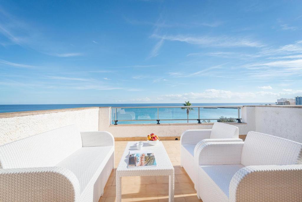 un balcón con sillas blancas, una mesa y el océano en Antic 302 en S'Illot