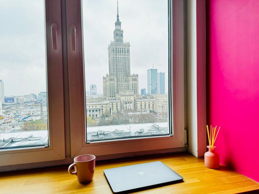 um computador portátil sentado numa secretária em frente a uma janela em -- View City Center Pink -- em Varsóvia