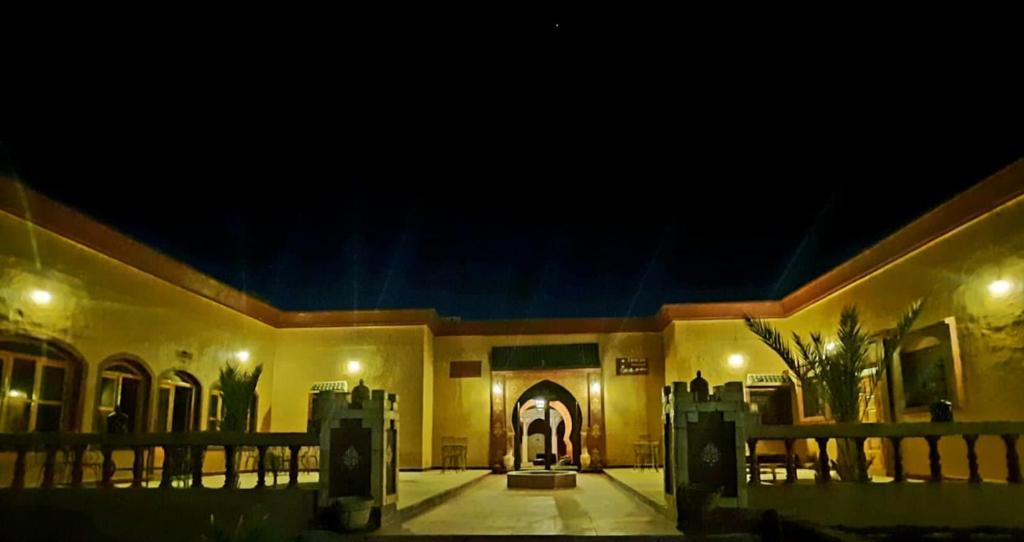 un edificio de noche con la puerta delantera iluminada en Riad family en Merzouga