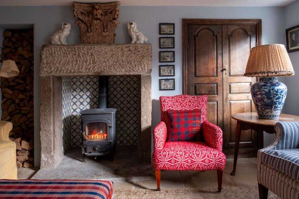 a living room with a red chair and a fireplace at Bert's - your idyllic Derbyshire retreat in Bonsall