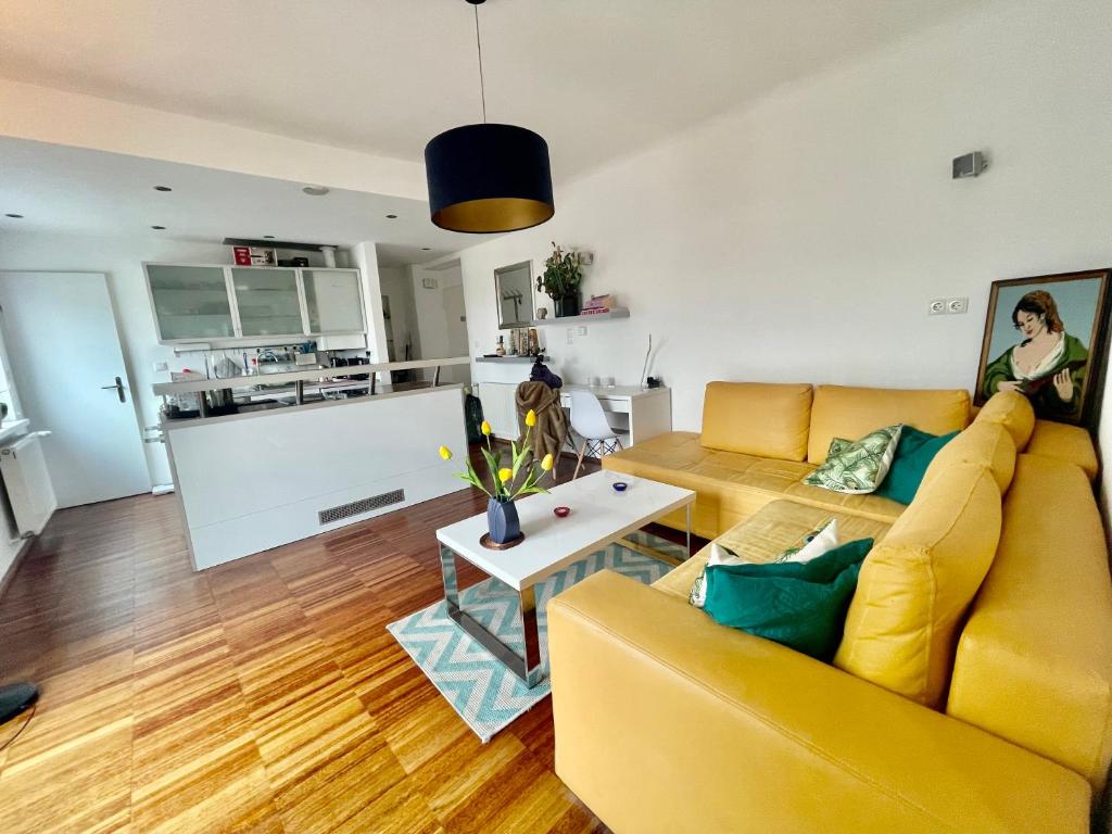 Cosy flat with huge Terrasse! Long or Shortterm في فيينا: غرفة معيشة مع أريكة صفراء وطاولة
