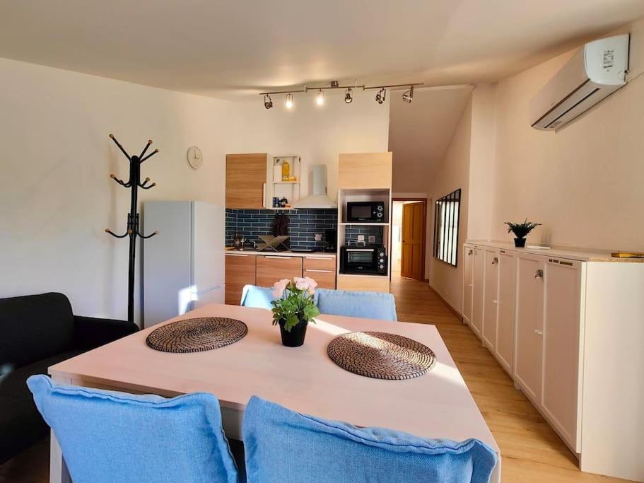 uma mesa de jantar com cadeiras azuis e uma cozinha em Appartement 2 chambres Terrasse em Orange