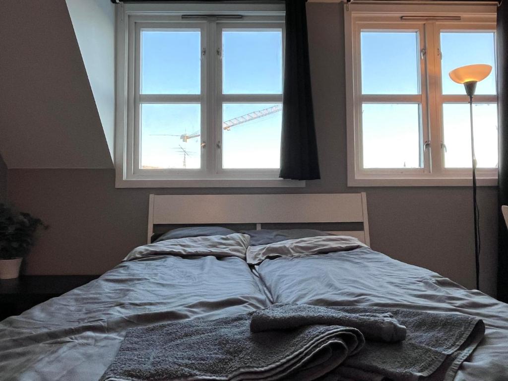 een bed met twee ramen en twee handdoeken erop bij cozy studio apartment in Trondheim