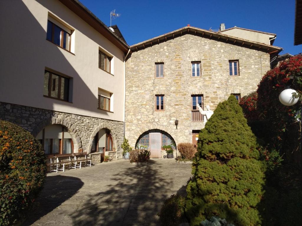 a large stone building with an archway in a courtyard at Casa de Colònies Casa Pare Coll in Gombreny