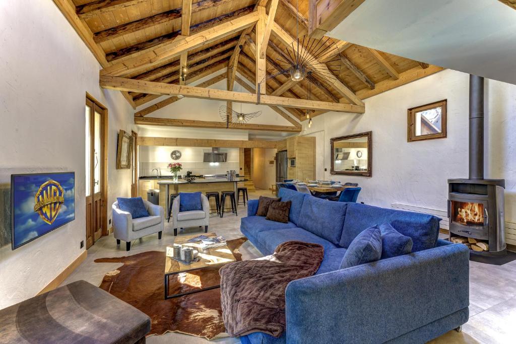 Chalet des Sapins في شامونيه مون بلان: غرفة معيشة مع أريكة زرقاء ومدفأة