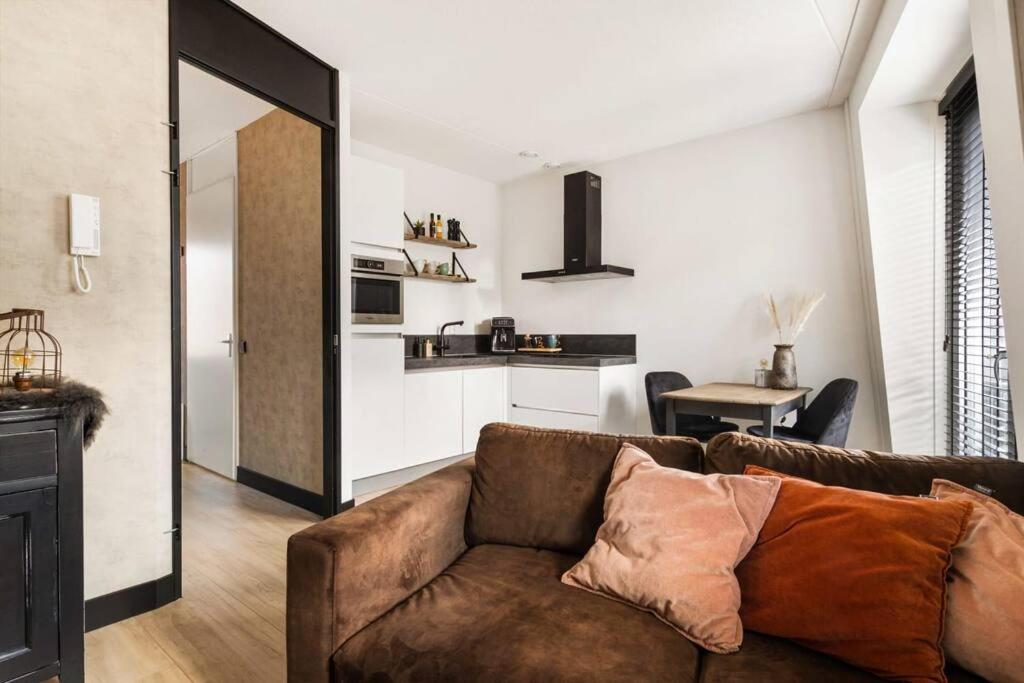 a living room with a brown couch and a kitchen at Atmospheric apartment Zaandam/Amsterdam in Zaandam