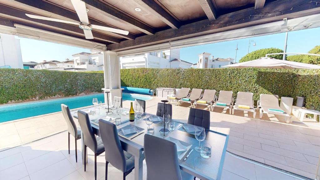 un patio con mesa de comedor y sillas y piscina en La Torre Villa Bacalao - A Murcia Holiday Rentals Property, en Roldán
