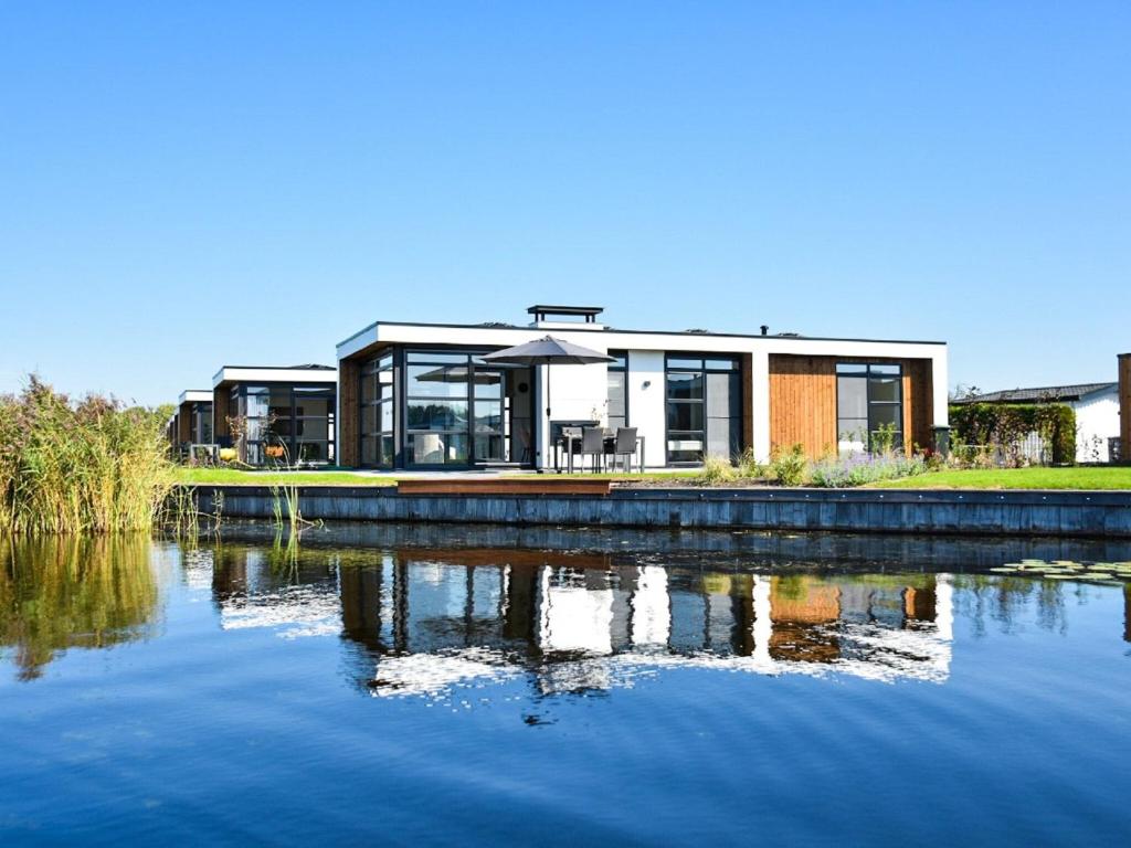 uma casa sentada em cima de uma massa de água em Beautiful holiday home in a holiday park near the Loosdrechtse Plassen em Nieuw-Loosdrecht