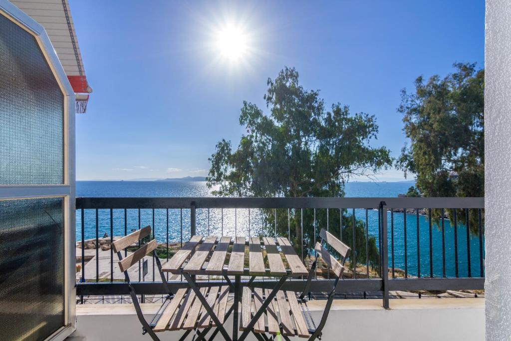 uma varanda com uma mesa e cadeiras e o oceano em Seafront Apartment in Piraeus em Piraeus