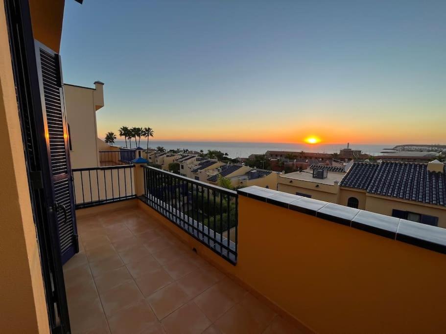 a balcony with a view of the sunset on a city at Triplex Meloneras-Amplio,soleado in Maspalomas