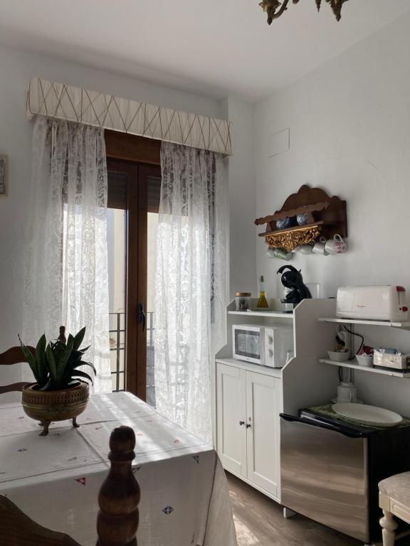 a kitchen with a table and a window with a microwave at Casa Rural Dolly Baby in Alarcón