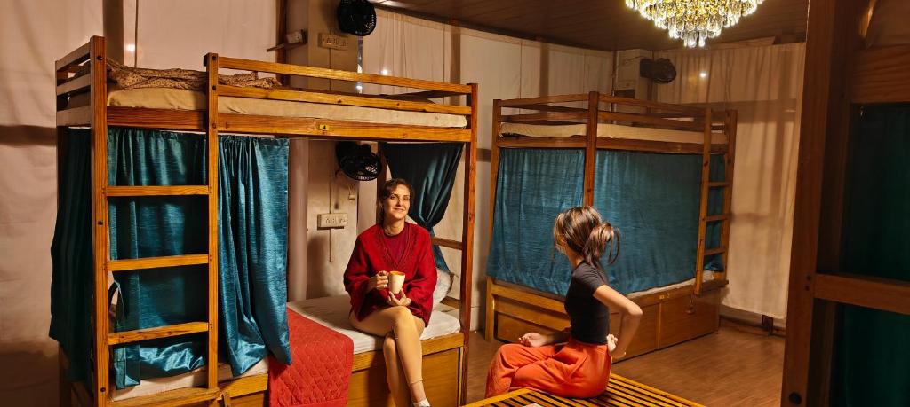 um homem e uma rapariga sentados numa cama num quarto com beliches em Moon Dance Hostel and Cafe em Pushkar