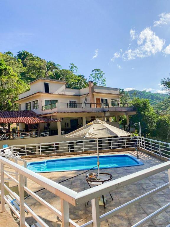 uma casa com piscina e guarda-sol em Sítio com lazer completo em meio a natureza em Marechal Floriano