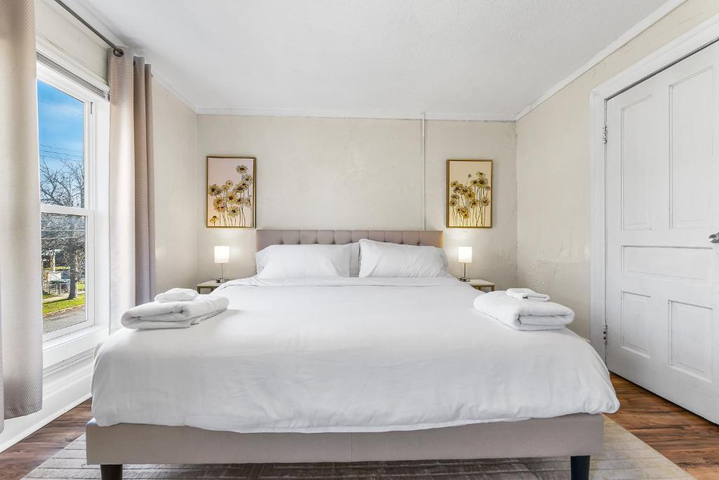 ein weißes Schlafzimmer mit einem großen weißen Bett und einem Fenster in der Unterkunft Contemporary Urban Home in Niagara Falls