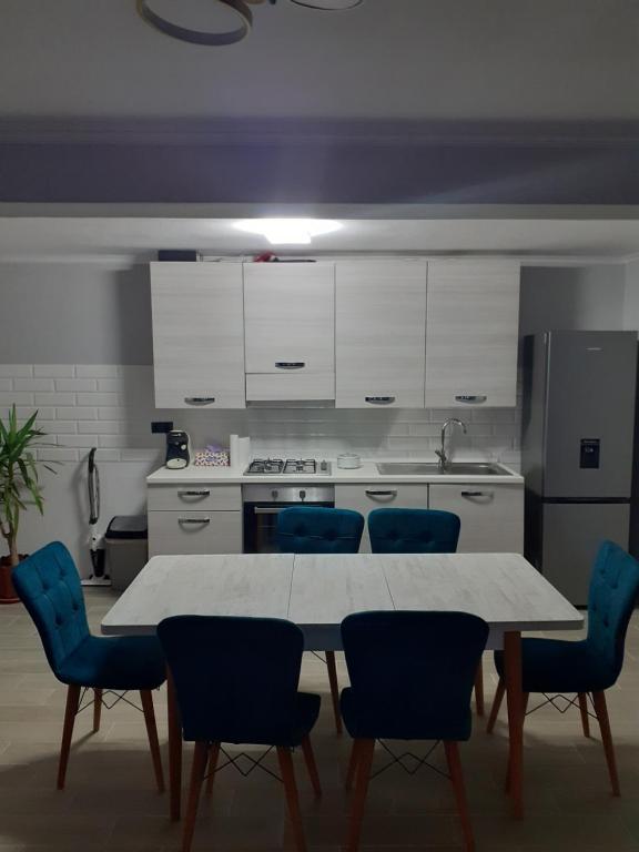 a kitchen with a white table and blue chairs at Casa Edy in Vişeu de Sus