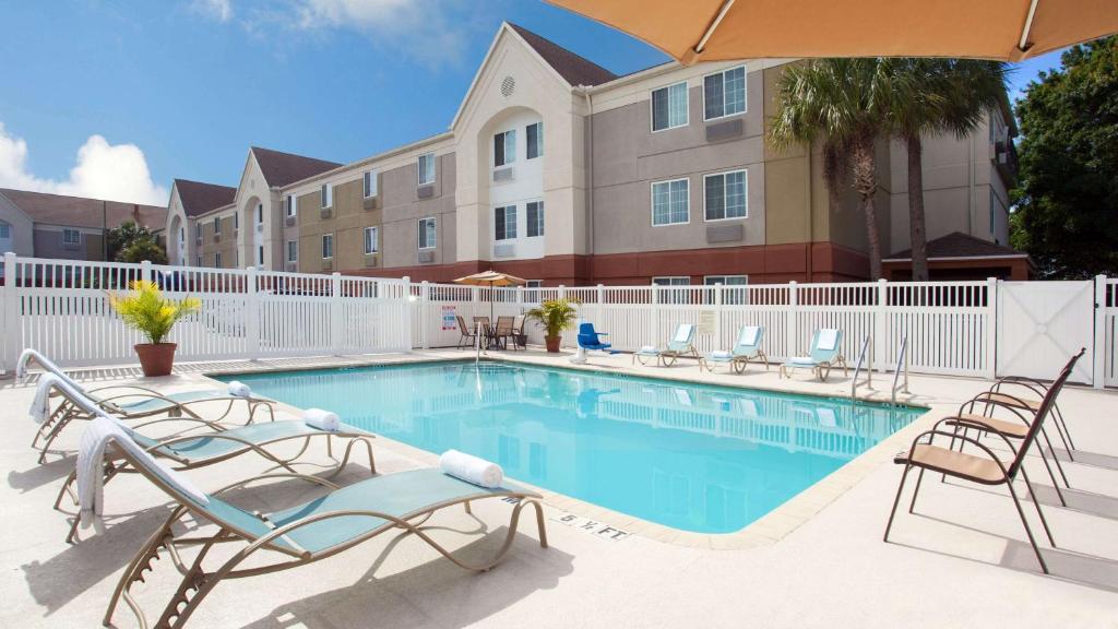 una piscina en un hotel con sillas y sombrilla en Sonesta Simply Suites Clearwater, en Clearwater