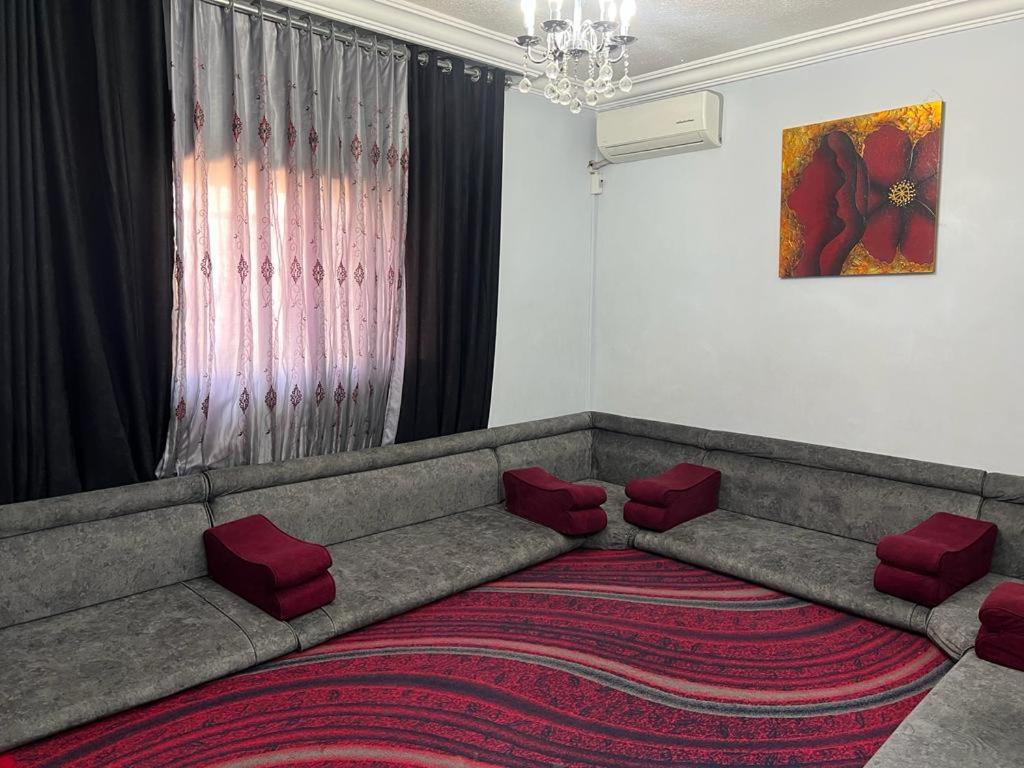Jad apartment في إربد: غرفة معيشة مع أريكة كبيرة مع وسائد حمراء