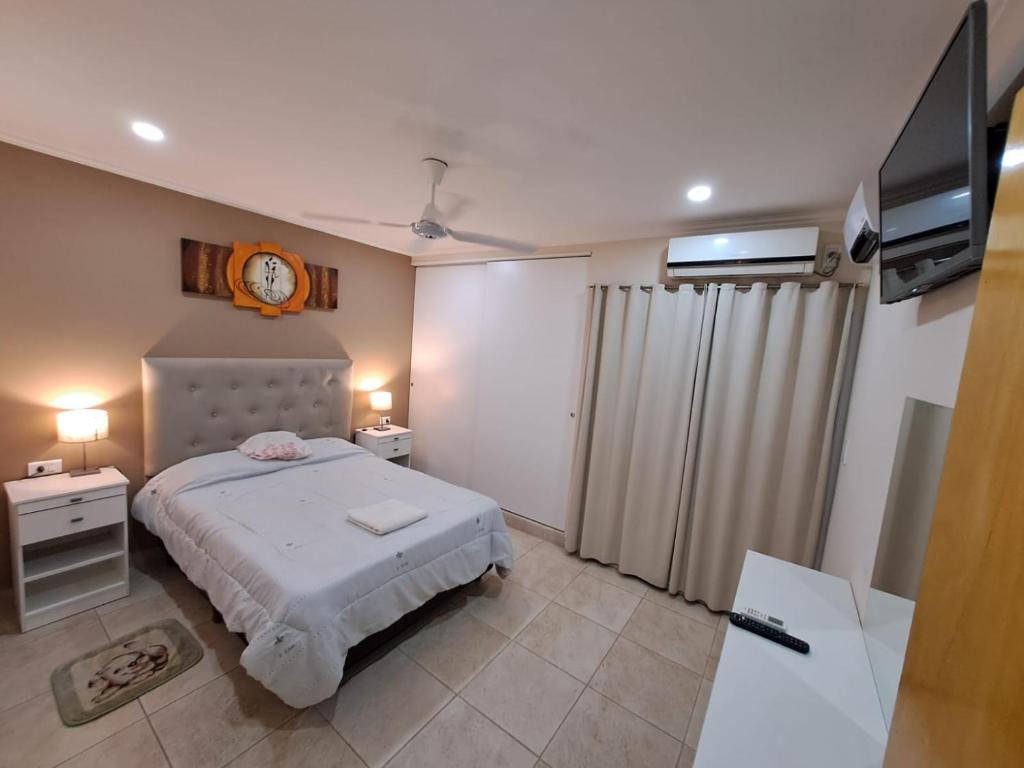聖地亞哥－德爾埃斯特羅的住宿－ALOJAMIENTO NORTE SGO，卧室配有一张床,墙上挂着一个钟