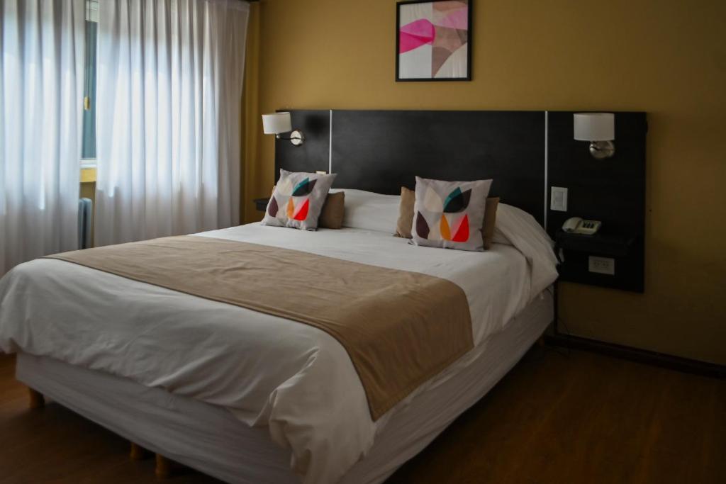 a bedroom with a large bed with white sheets and pillows at Hotel San Carlos in General Juan Madariaga