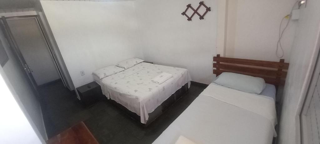 a small room with two beds and a mirror at Pousada Elefantinho in São Pedro da Aldeia