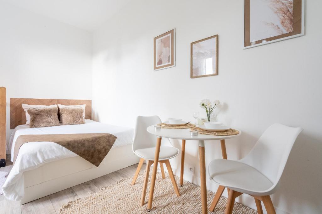 une chambre avec un lit, une table et des chaises dans l'établissement Le César Cinéma 10 mn Paris Gare de Lyon et 5 minutes RER, à Alfortville