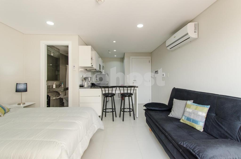 a bedroom with a bed and a couch and a kitchen at Modern Studio Apartment In Los Laureles in Asunción